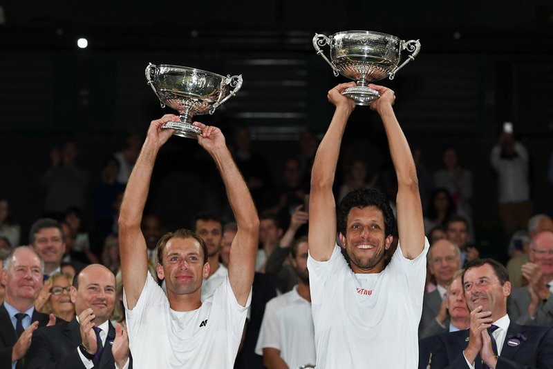 Poland's Lukasz Kubot (L) and Brazil's Marcelo Melo (R) hold up their winners' trophies during the presentation after beating Austria's Oliver Marach and Croatia's Mate Pavic during their men's doubles final match on the twelfth day of the 2017 Wimbledon Championships at The All England Lawn Tennis Club in Wimbledon, southwest London, on July 15, 2017. / AFP PHOTO / Glyn KIRK / RESTRICTED TO EDITORIAL USE