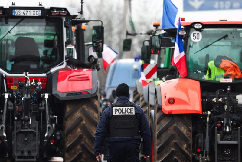 A French CRS police officer walk between tractors blocking the A6 highway near Chilly-Mazarin, south of Paris, on February 1, 2024 as French farmers maintain roadblocks on key highways into Paris for a third day, as part of nationwide protests called by several farmers' unions over pay, tax and regulations. French farmers protesting over pay, tax and regulation kept up their roadblocks on February 1, 2024 as eyes turned to Brussels in hope of more European Union concessions. Seven blockades remained in place on motorways around Paris late January 31, throttling access to the capital. (Photo by EMMANUEL DUNAND / AFP)<!-- NICAID(15666578) -->