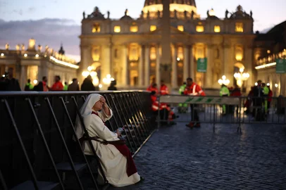 A nun sits on a fence in front of St Peter's Basilica of the Vatican, in the Vatican on April 25, 2025. The Vatican on April 24 said some 61,000 people had already paid their respects to Pope Francis, whose body is lying in state in St Peter's Basilica ahead of his funeral. (Photo by HENRY NICHOLLS / AFP)<!-- NICAID(16024451) -->