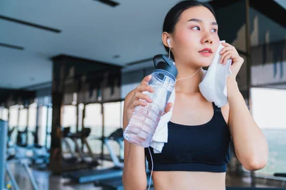 asian healthy aport woman relaxing in gym after workout hand hold pure water drink and white towelFonte: 273438127<!-- NICAID(15744852) -->