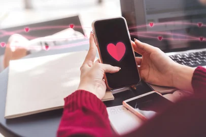 People youth culture dating online with application concept. Cloes up young woman hand using mobile phone with heart icon on device screen for meet up new love couple relationship.<!-- NICAID(15994764) -->