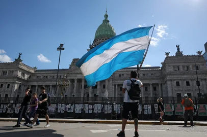 A demonstrator holds an Argentinian national flag outside the Congress building, where Argentina's President Javier Milei's labour reform is being treated, in Buenos Aires, on February 19, 2026. Shops and supermarkets closed, public transport was scarce and garbage went uncollected on February 19, 2026 as Argentine workers staged the fourth general strike of President Javier Milei's term, this time to protest labor reforms. (Photo by TOMAS CUESTA / AFP)Editoria: LABLocal: Buenos AiresIndexador: TOMAS CUESTASecao: governmentFonte: AFPFotógrafo: STF<!-- NICAID(16228751) -->