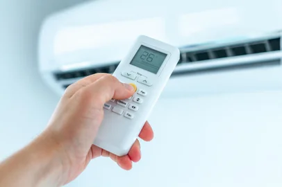 Air conditioner temperature adjustment with remote controller in room at home. Fonte: 272777314<!-- NICAID(14997287) -->