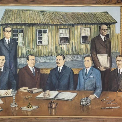 Direção da Metalúrgica Abramo Eberle retratada por Robinson Sobrera na década de 1970. Ao centro estão Abramo Eberle e os filhos José Eberle (E) e Júlio João Eberle. Nas laterais, os diretores (à esquerda) Caetano Pettinelli, Erico Raabe (de óculos) e Hugo Argenta (sentado). À direita, Oscar Martini e Pedro Moré (em pé) e Riccieri Serafini e Pedro Eberle (sentados). Quadro traz ainda, sobre a mesa, os símbolos, as marcas registradas e toda a produção da metalúrgica ao longo dos tempos. A partir da esquerda, conjunto de talheres, artigo sacro, a piteira, o triângulo (AEC), a lamparina, os motores, as facas de gaúcho e os apetrechos de selaria e montaria. Ao fundo, a casinha de madeira, réplica da primeira funilaria, fundada em 1896.<!-- NICAID(15731664) -->