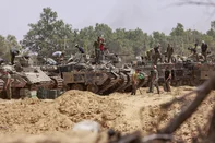 Israeli troops work on their armoured vehicles at a position by Israel's border with the Gaza Strip on May 18, 2025. Israel's military has announced a day earlier the expansion of its operations, saying it is aimed at "achieving all the war's objectives" including releasing hostages and "the defeat of Hamas", the Palestinian movement that runs Gaza. (Photo by Menahem KAHANA / AFP)<!-- NICAID(16040030) -->