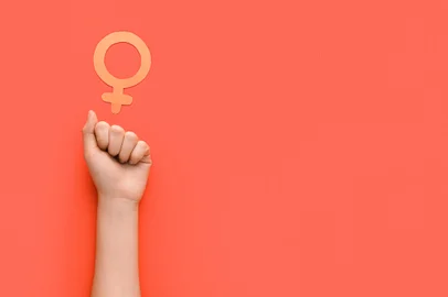 Female hand with clenched fist and symbol of woman on red background with space for text. Concept of feminismFonte: 562211672<!-- NICAID(15423096) -->