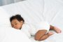 black african american baby sleeping on a white mattress.Fonte: 440423807<!-- NICAID(15565313) -->