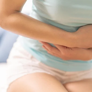 Young woman suffering from abdominal pain while sitting on the sofa and feeling stomachache, symptom of pmsFonte: 200888246<!-- NICAID(14909796) -->