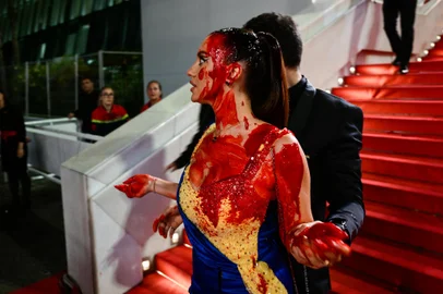 A protester, wearing a dress in the colours of the Ukrainian flag, is detained by security after she covered herself in fake blood on the stairs on the Festival Palace ahead of the screening of the film "Acide" during the 76th edition of the Cannes Film Festival in Cannes, southern France, on May 21, 2023. (Photo by CHRISTOPHE SIMON / AFP)<!-- NICAID(15435102) -->
