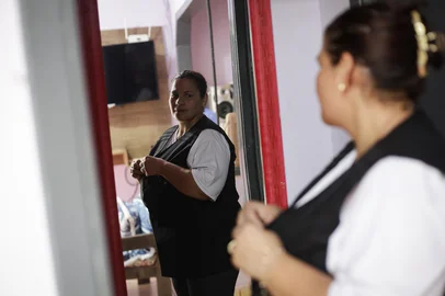 GRAVATAÍ, RS, BRASIL, 25-02-2026: A babá Sílvia Regina da Silva Paixão Teixeira, 43 anos, veste seu uniforme de trabalho em casa, no bairro Vera Cruz, em Gravataí. Ela começou trabalhando como doméstica, depois passou a atuar como babá. Hoje, há quase 20 anos na profissão, com dezenas de cursos de formação relacionados à área, além de ser técnica em enfermagem e socorrista, ela atende famílias de alta renda. Foto: Mateus Bruxel/Agência RBSIndexador: MATEUS BRUXEL<!-- NICAID(16232389) -->