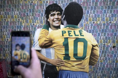A man takes a picture of a wall depicting an image of late football stars Diego Maradona of Argentina and Pele of Brazil embracing each other, in Buenos Aires on December 29, 2022, just hours after the passing of Pele. (Photo by Juan MABROMATA / AFP)Editoria: SPOLocal: Buenos AiresIndexador: JUAN MABROMATASecao: soccerFonte: AFPFotógrafo: STF<!-- NICAID(15307983) -->