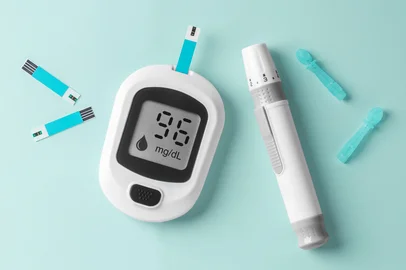 Blood glucose meter, diabetes checking sugar level on light green background, top view<!-- NICAID(16173454) -->