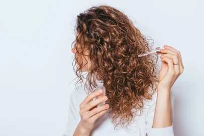 Mulher aplicando cosmético no cabelo - Foto: progressman/stock.adobe.comFonte: 320158313<!-- NICAID(15786540) -->