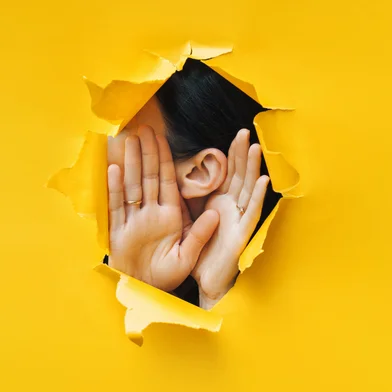 Female ear and hands close-up. Copy space. Torn paper, yellow background. The concept of eavesdropping, espionage, gossip and the yellow press.Female ear and hands close-up. Copy space. Torn paper, yellow background. The concept of eavesdropping, espionage, gossip and the yellow press. Foto: shchus  / stock.adobe.comFonte: 285286400<!-- NICAID(16078412) -->