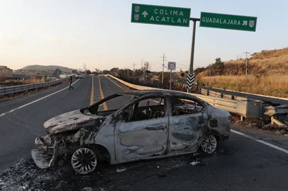 A view of a burned car, allegedly set on fire by organised crime groups in response to an operation to arrest a high-priority security target, on a highway near Acatlan de Juarez, Jalisco state, Mexico on February 22, 2026. The Mexican army announced that it had killed powerful drug lord Nemesio "El Mencho" Oseguera in an operation that sparked a wave of violence in various parts of the country on February 22, 2026. Gunmen retaliating for the raid blocked more than 20 roads in western Jalisco state, which includes Tapalpa, with burning cars and trucks. The violence spread to other states as well. (Photo by Ulises Ruiz / AFP)<!-- NICAID(16231048) -->