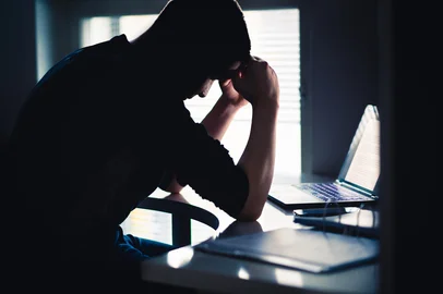 Stress at work. Tired man with anxiety. Sad office worker with laptop. Frustrated university or college student. Dark silhouette of  anxious person. Home computer. Bad problem with business.Fonte: 1197164724<!-- NICAID(15998013) -->