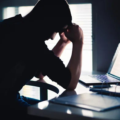 Stress at work. Tired man with anxiety. Sad office worker with laptop. Frustrated university or college student. Dark silhouette of  anxious person. Home computer. Bad problem with business.Fonte: 1197164724<!-- NICAID(15998013) -->