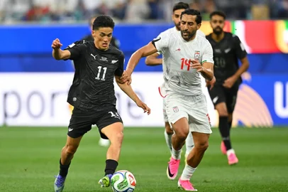 New Zealand's forward #11 Elijah Just and Iran's midfielder #14 Saman Ghoddos fight for the ball during the 2026 World Cup Group G football match between Iran and New Zealand at Los Angeles Stadium in Inglewood on June 15, 2026.  (Photo by Patrick T. Fallon / AFP)<!-- NICAID(16307159) -->