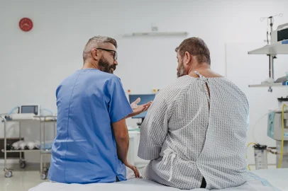 Supportive doctor soothing a worried overweight patient, discussing test result in emergency room. Illnesses and diseases in middle-aged men's health. Compassionate physician supporting stressed patient. Concept of health risks of overwight and obesity.Supportive doctor soothing worried overweight patient, discussing test result in emergency room. Illnesses and diseases in middle-aged men's health. Compassionate physician supporting stressed patient. Concept of health risks of overwight and obesity.Fonte: 669882098<!-- NICAID(15908719) -->