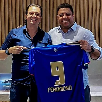Handout picture released by the Cruzeiro Esporte football club showing its president Sergio Santos Rodrigues (L) and Brazilian former striker Ronaldo (R) posing for a picture holding a Cruzeiro jersey, during a meeting in Sao Paulo, Brazil, on December 18, 2021. - Former Brazilian striker Ronaldo announced on Saturday that he would buy Cruzeiro, a club where he made his professional debut at the age of 16, but which has languished in the second division for two seasons. (Photo by Cruzeiro Football Club / AFP) / RESTRICTED TO EDITORIAL USE - MANDATORY CREDIT AFP PHOTO / CRUZEIRO FOOTBALL CLUB - NO MARKETING NO ADVERTISING CAMPAIGNS -DISTRIBUTED AS A SERVICE TO CLIENTSEditoria: SPOLocal: Sao PauloIndexador: -Secao: soccerFonte: Cruzeiro Football ClubFotógrafo: Handout<!-- NICAID(14972117) -->