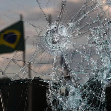 A Brazilian flag is reflected on a broken window of the Supreme Court building in Brasilia on January 10, 2023, two days after thousands of supporters of Brazil's far-right ex-president Jair Bolsonaro raided federal buildings. - President Luiz Inacio Lula da Silva condemned "acts of terrorism" after a far-right mob stormed the seat of power, unleashing chaos on the capital. (Photo by CARL DE SOUZA / AFP)Editoria: WARLocal: BrasíliaIndexador: CARL DE SOUZASecao: crisisFonte: AFPFotógrafo: STF<!-- NICAID(15317834) -->