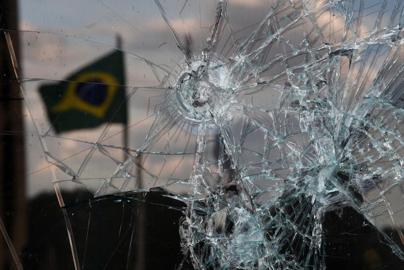 A Brazilian flag is reflected on a broken window of the Supreme Court building in Brasilia on January 10, 2023, two days after thousands of supporters of Brazil's far-right ex-president Jair Bolsonaro raided federal buildings. - President Luiz Inacio Lula da Silva condemned "acts of terrorism" after a far-right mob stormed the seat of power, unleashing chaos on the capital. (Photo by CARL DE SOUZA / AFP)Editoria: WARLocal: BrasíliaIndexador: CARL DE SOUZASecao: crisisFonte: AFPFotógrafo: STF<!-- NICAID(15317834) -->
