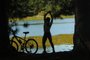 Exercício Físico. Jovens fazendo alongamento e ciclismo na beira da lagoa.<!-- NICAID(6927847) -->