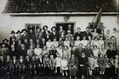 Escola Municipal de São Luiz na Terceira Légua - Caxias do Sul, em 1930. Estão reunidos pais, alunos, professores e autoridades. Na primeira fila, sentadas, da esquerda para a direita, as professoras Maria Foppi e Maria Prezzi Postali.Fonte: B3459, doação de Aparício Postali, Arquivo Histórico Municipal João Spadari Adami.<!-- NICAID(16036517) -->