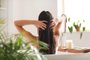 Young woman applying coconut oil onto her hair in bathroomIndexador: LEONID IASTREMSKYIFonte: 510232247<!-- NICAID(15489323) -->