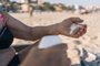 Hands of retired senior woman on vacation smearing cream on her hand. Close-up image of an elderly lady on the sand at the beach putting sunscreen on her hand to protect herself from UV rays.Fonte: 624091681<!-- NICAID(15636073) -->