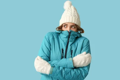 Frozen young woman in warm winter clothes on blue backgroundIndexador: Leonid IastremskyiFonte: 690413846<!-- NICAID(15786606) -->