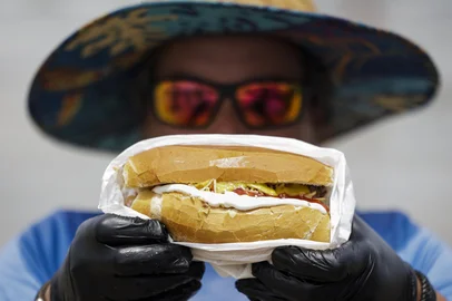 TORRES, RS, BRASIL, 16-01-2026: Ambulante Leomar Delgado vende choripan à beira-mar em Torres, no Litoral Norte. Fluxo de turistas argentinos impulsiona o comércio desse lanche tradicional do país vizinho em praias gaúchas. Foto: Mateus Bruxel/Agência RBSIndexador: MATEUS BRUXEL<!-- NICAID(16205536) -->