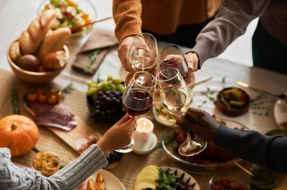 Multiethnic group of friends at festive dinner table celebrating Thanksgiving together and enjoying homemade dishes, copy space<!-- NICAID(15887485) -->