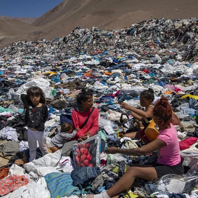 Women search for used clothes amid tons discarded in the Atacama desert, in Alto Hospicio, Iquique, Chile, on September 26, 2021. - EcoFibra, Ecocitex and Sembra are circular economy projects that have textile waste as their raw material. The textile industry in Chile will be included in the law of Extended Responsibility of the Producer (REP), forcing clothes and textiles importers take charge of the waste they generate. (Photo by MARTIN BERNETTI / AFP)<!-- NICAID(14936969) -->