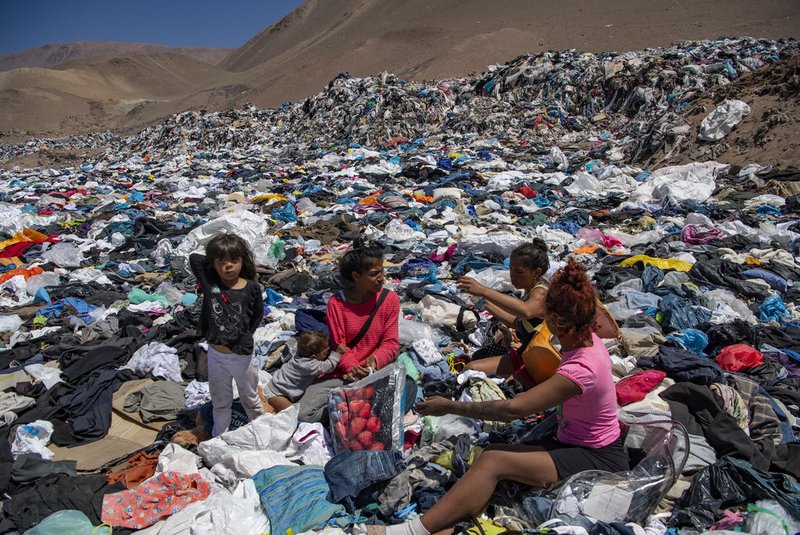 Women search for used clothes amid tons discarded in the Atacama desert, in Alto Hospicio, Iquique, Chile, on September 26, 2021. - EcoFibra, Ecocitex and Sembra are circular economy projects that have textile waste as their raw material. The textile industry in Chile will be included in the law of Extended Responsibility of the Producer (REP), forcing clothes and textiles importers take charge of the waste they generate. (Photo by MARTIN BERNETTI / AFP)<!-- NICAID(14936969) -->