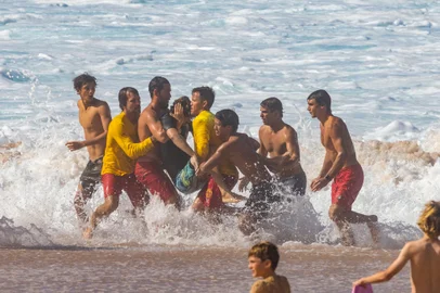 People carry Brazilian surfer Joao Chianca who wiped out while practicing for the upcoming Vans 2023 Pipeline Masters event at Banzai Pipeline in Haleiwa, Oahu's north shore, Hawaii, on December 3, 2023. Brazilian surfer Joao Chianca was rushed to the hospital. (Photo by Brian Bielmann / AFP) / RESTRICTED TO EDITORIAL USE<!-- NICAID(15615677) -->