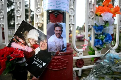 Flowers and pictures to former One Direction singer Liam Payne are displayed on a bandstand following the singer's death, in Wolverhampton, central England on November 11, 2024. Payne was found dead on October 16, 2024, after falling from the balcony of his third-floor room at the Casa Sur Hotel in the Argentinian capital. Hotel staff had called emergency services twice to report a guest "overwhelmed by drugs and alcohol" who was "destroying" a hotel room. (Photo by Paul ELLIS / AFP)<!-- NICAID(15917248) -->