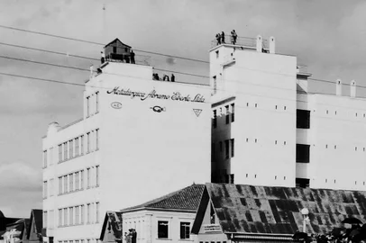 Depois das visitas guiadas realizadas em dezembro, integrando a programação do Natal de Afetos, e outras três durante a Festa Nacional da Uva, o Pátio Eberle incluiu os passeios pela história do prédio em sua programação mensal. Sob a orientação deste colunista, haverá visitas guiadas ao terraço e outros pontos históricos do edifício sempre no primeiro sábado de cada mês. Os participantes poderão conhecer mais sobre a história e as curiosidades de símbolos arquitetônicos do centro de Caxias, como a casinha de madeira, relógio e a famosa “piteira”, situada em dois pontos do telhado. Legenda: Grupo no entorno da casinha da Metalúrgica Abramo Eberle (atual Pátio Eberle), conferindo a programação do Congresso Eucarístico Diocesano, em maio de 1948.<!-- NICAID(15722032) -->