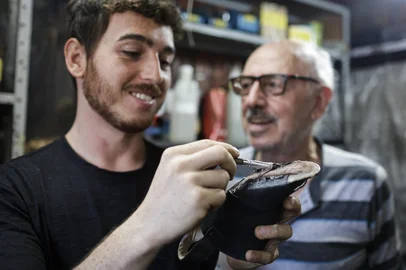 Porto Alegre, RS, Brasil, 28-04-2025: O sapateiro Vitor Barth, 86 anos, trabalha com o neto Hiago na Sapataria Modelo, no bairro Azenha. Ele atua há mais de 50 anos na profissão e já passou os conhecimentos para o filho e o neto também trabalharem como sapateiros. Foto: Mateus Bruxel / Agência RBSIndexador: MATEUS BRUXEL<!-- NICAID(16025744) -->