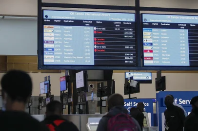 Travellers walk near an electronic flight notice board displaying cancelled flights  at OR Tambo International Airport in Johannesburg on November 27, 2021, after several countries banned flights from South Africa following the discovery of a new Covid-19 variant Omicron. - A flurry of countries around the world have banned ban flights from southern Africa following the discovery of the variant, including the United States, Canada, Australia,Thailand, Brazil and several European countries. The main countries targeted by the shutdown include South Africa, Botswana, eSwatini (Swaziland), Lesotho, Namibia, Zambia, Mozambique, Malawi and Zimbabwe. (Photo by Phill Magakoe / AFP)Editoria: HTHLocal: JohannesburgIndexador: PHILL MAGAKOESecao: diseaseFonte: AFPFotógrafo: STR<!-- NICAID(14958413) -->