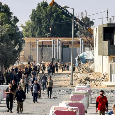Palestinian workers, who were stranded in Israel since the October 7 attacks, walk near the Rafah border crossing with Egypt as they make their way to cross back into the Gaza Strip at the Kerem Shalom commercial border crossing with Israel in the south of the Palestinian enclave on November 3, 2023. (Photo by SAID KHATIB / AFP)<!-- NICAID(15587300) -->