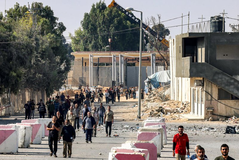 Palestinian workers, who were stranded in Israel since the October 7 attacks, walk near the Rafah border crossing with Egypt as they make their way to cross back into the Gaza Strip at the Kerem Shalom commercial border crossing with Israel in the south of the Palestinian enclave on November 3, 2023. (Photo by SAID KHATIB / AFP)<!-- NICAID(15587300) -->