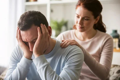 Adobe Stock - trabalho emocionalMan burying head in hands while woman comforts him. Concept of mankeeping and womenâs invisible emotional labor in relationships. Generative aiFonte: 1565969012<!-- NICAID(16094084) -->