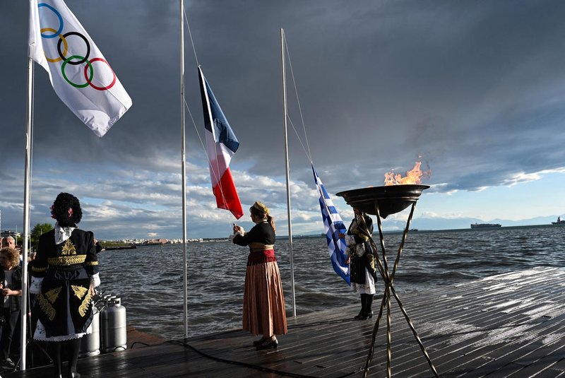 This photograph taken on April 21, 2024, shows a cauldron with the Olympic flame next to the Olympic flag, in the waterfront of Thessaloniki, during the Olympic torch relay. (Photo by Sakis MITROLIDIS / AFP)Editoria: SPOLocal: ThessalonikiIndexador: SAKIS MITROLIDISSecao: sports eventFonte: AFPFotógrafo: STR<!-- NICAID(15746094) -->