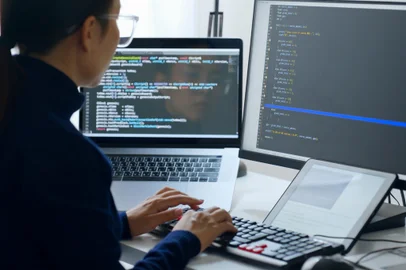 Young Asian woman, developer programmer, software engineer, IT support, wearing glasses working on computer to check coding in bugging system. Back viewFonte: 500709335<!-- NICAID(15185742) -->