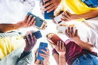 Teens in circle holding smart mobile phones - Multicultural young people using cellphones outside - Teenagers addicted to new technology concept<!-- NICAID(16304827) -->