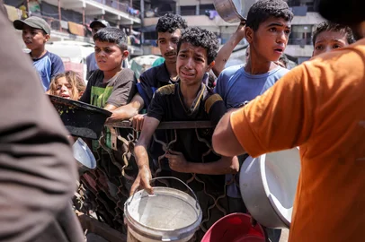 Children queue with pots to receive meals from a charity kitchen in Gaza City on July 14, 2025. With the war in Gaza now in its 22nd month and Israel only slightly easing an aid blockade of the Palestinian territory, shortages of everything from food to clean water have hit everyone. (Photo by BASHAR TALEB / AFP)Editoria: SOILocal: Gaza CityIndexador: BASHAR TALEBSecao: charityFonte: AFPFotógrafo: STR<!-- NICAID(16083616) -->
