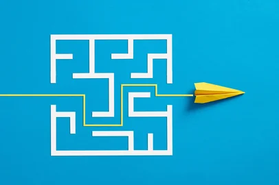 Cagkan / adobe.stock.com Overcoming the barriers. Conquering the obstacles. Way to success and business solutions. Exit strategy. Paper plane breaking through the maze on blue background.Indexador: Cagkan SayinFonte: 573447072<!-- NICAID(16385644) -->