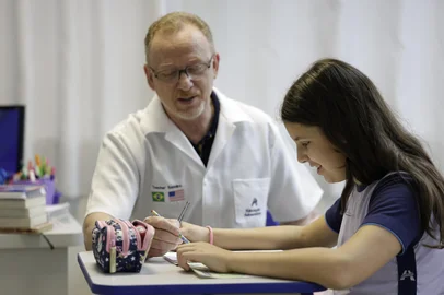 PORTO ALEGRE, RS, BRASIL, 30-09-2025: O professor de Língua Inglesa Sandro Moraes e a aluna do 5o ano Elisa Sebotaio Rodrigues em sala de aula no Colégio Adventista Marechal Rondon, na Vila Ipiranga. Reportagem sobre ensino de idiomas x escolas bilíngues, explicando diferenças e recursos pedagógicos usados no ensino de línguas na educação básica, para o caderno Guia da Escola. Foto: Mateus Bruxel/Agência RBSIndexador: MATEUS BRUXEL<!-- NICAID(16135996) -->