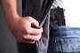 *A PEDIDO DE FILIPE PIMENTEL* A man reveals a concealed pistol at his side. - Foto: ustinkendra/stock.adobe.com Fonte: 45137987<!-- NICAID(15163429) -->